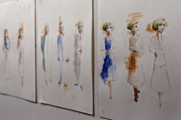 Four sheets of paper display fashion sketches of women wearing vintage-style outfits in light colours, with some designs outlined in pencil and partially coloured with blue, brown, or beige watercolour.